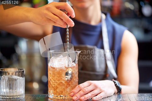 Image of bartender with cocktail stirrer and glass at bar