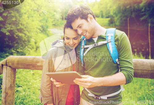 Image of happy couple with backpacks and tablet pc outdoors