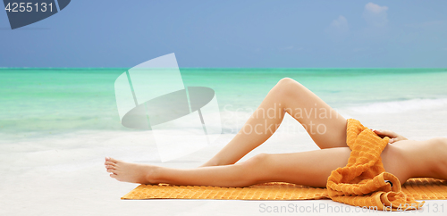 Image of legs of bare woman lying in towel on beach