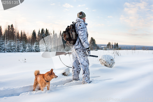 Image of hunter with dog on the snowy road