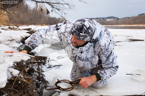 Image of hunter putting a leghold trap for beaver