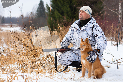 Image of hunter with gun and dog in winter