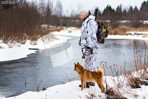 Image of hunter with his dog on the river bank