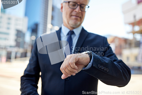 Image of senior businessman with wristwatch on city street