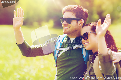 Image of happy couple with backpacks hiking outdoors