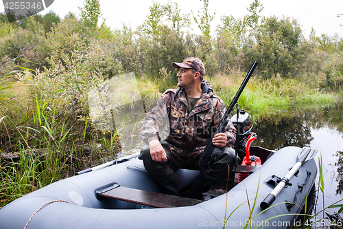 Image of hunter with a gun in the boat