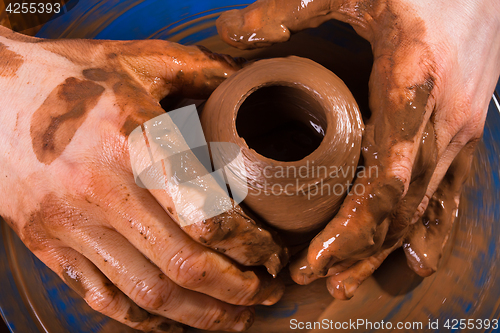 Image of hands of potter on  pottery wheel, closeup