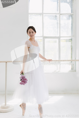 Image of Young and incredibly beautiful ballerina is posing and dancing in a white studio