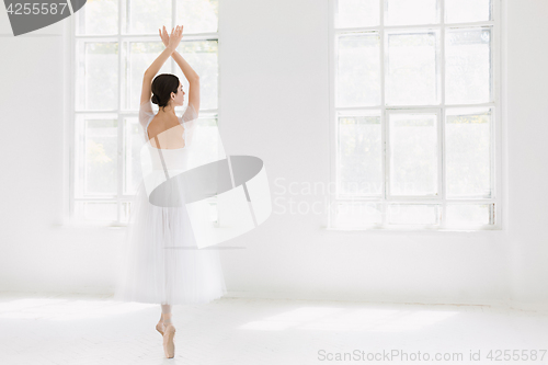 Image of Young and incredibly beautiful ballerina is posing and dancing in a white studio