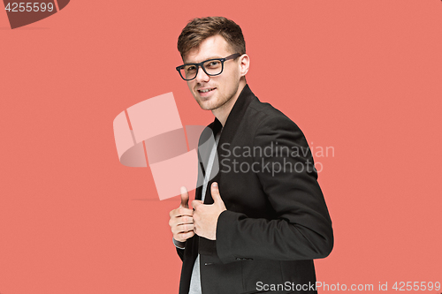 Image of Young handsome man in black suit and glasses isolated on red background