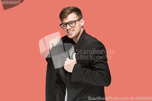 Image of Young handsome man in black suit and glasses isolated on red background