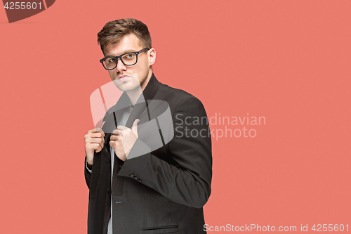 Image of Young handsome man in black suit and glasses isolated on red background