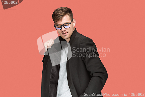 Image of Young handsome man in black suit and glasses isolated on red background