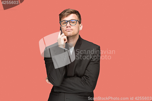 Image of The young caucasian businessman on red background talking on cell phone