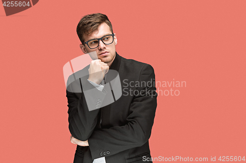 Image of Young handsome man in black suit and glasses isolated on red background