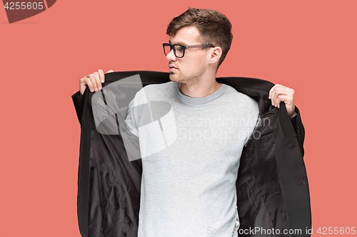 Image of Young handsome man in black suit and glasses isolated on red background