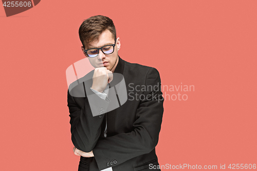 Image of Young handsome man in black suit and glasses isolated on red background