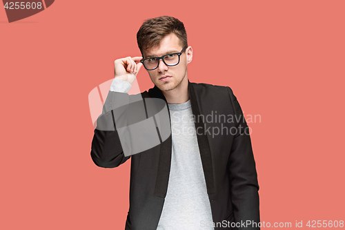 Image of Young handsome man in black suit and glasses isolated on red background