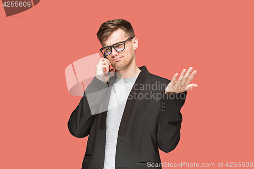 Image of The young caucasian businessman on red background talking on cell phone