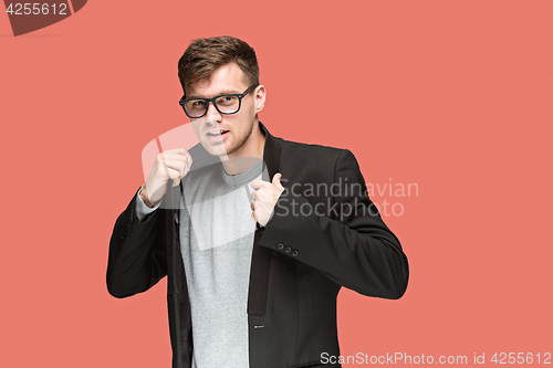 Image of Young handsome man in black suit and glasses isolated on red background