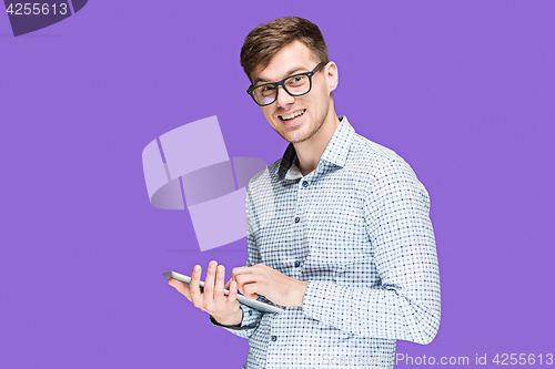 Image of The young man in a shirt working on laptop on lilac backgroundin