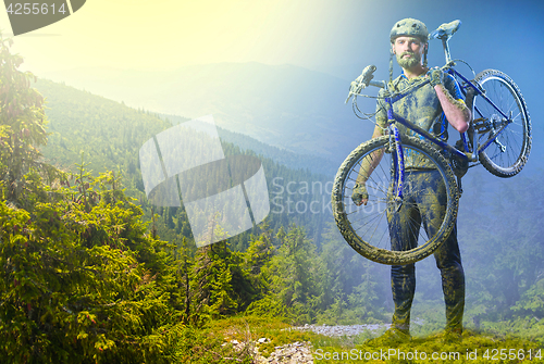 Image of The man with bike in sand standing on mountains background. Collage