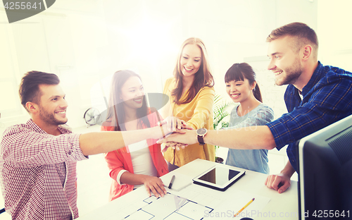 Image of creative team holding hands together  at office