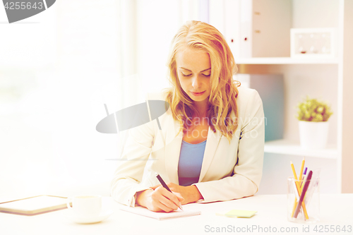 Image of businesswoman writing to notebook at office