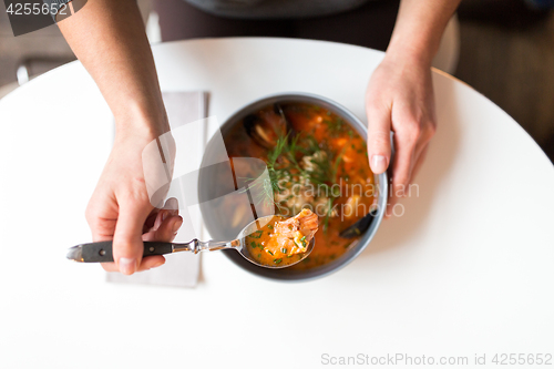 Image of woman eating seafood soup at restaurant