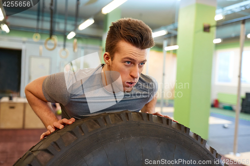 Image of man doing strongman tire flip training in gym