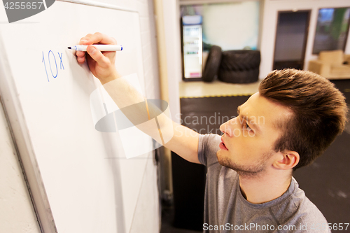 Image of man writing numbers to whiteboard in gym