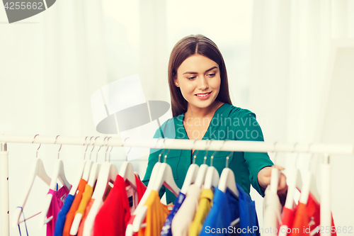 Image of happy woman choosing clothes at home wardrobe