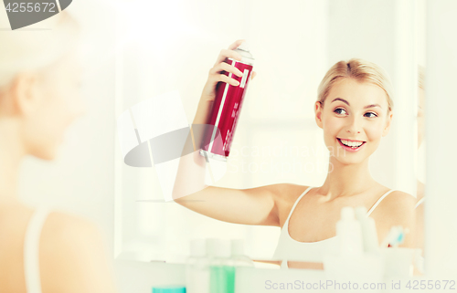 Image of woman with hairspray styling her hair at bathroom