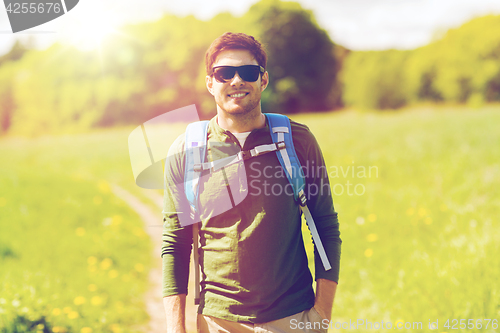 Image of happy young man with backpack hiking outdoors