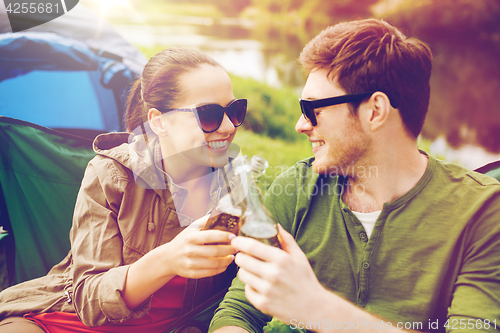 Image of happy couple clinking drinks at campsite tent