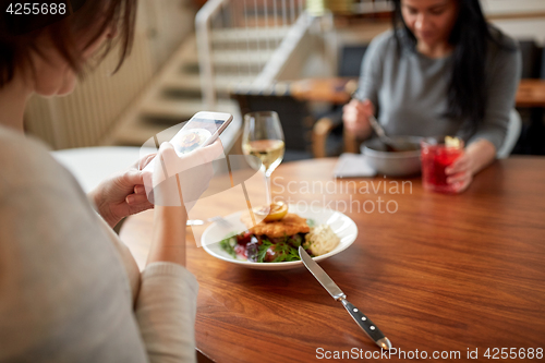 Image of women with smartphones and food at restaurant