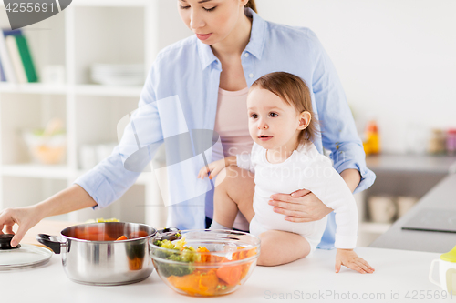 Image of happy mother and baby cooking vegetables at home