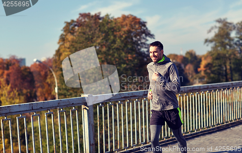 Image of happy young man running over city bridge