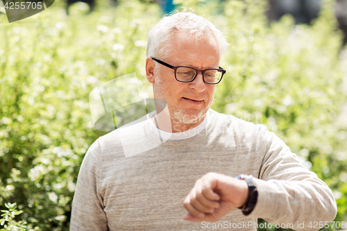 Image of senior man checking time on his wristwatch