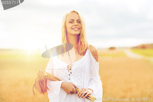 Image of happy young woman with spikelets on cereal field