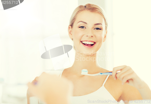 Image of woman with toothbrush cleaning teeth at bathroom