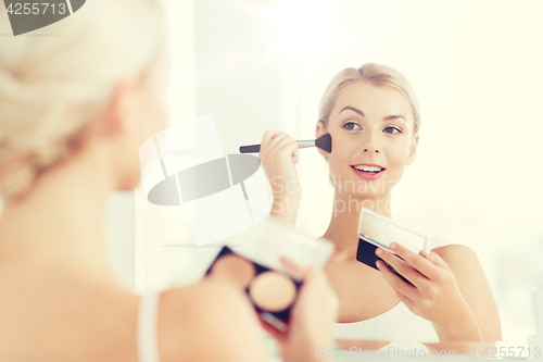 Image of woman with makeup brush and foundation at bathroom