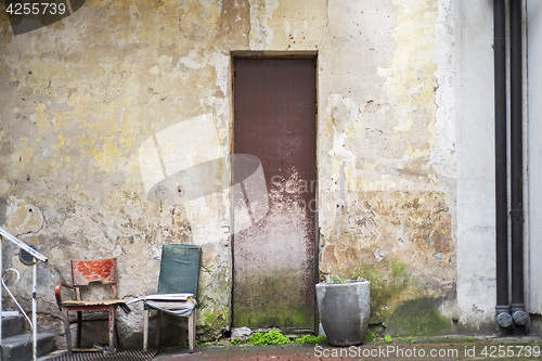 Image of Pot for flowers, two chairs near abandoned grunge cracked wall