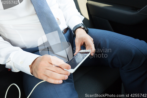 Image of Close up of businessman using mobile smart phone in a car.
