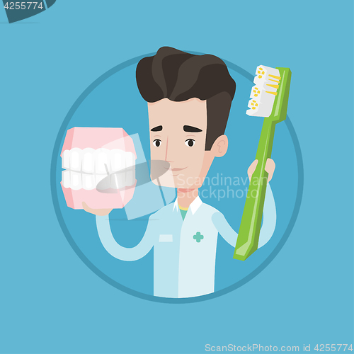 Image of Dentist with dental jaw model and toothbrush.