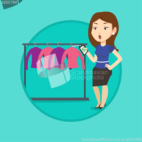 Image of Woman shocked by price tag in clothing store.