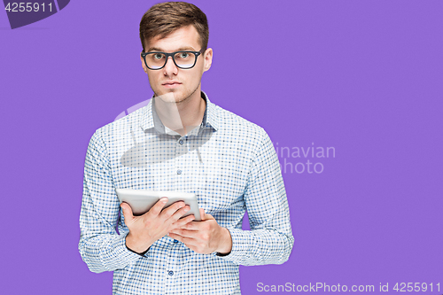 Image of The young man in a shirt working on laptop on lilac backgroundin