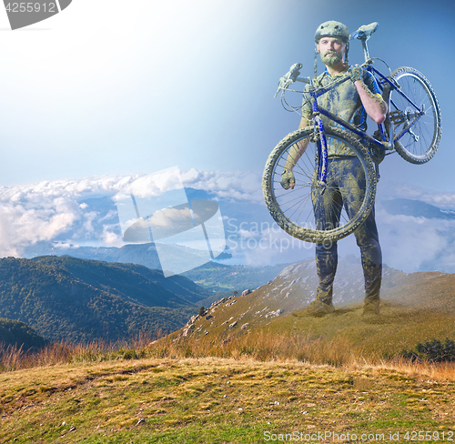 Image of The man with bike in sand standing on mountains background. Collage