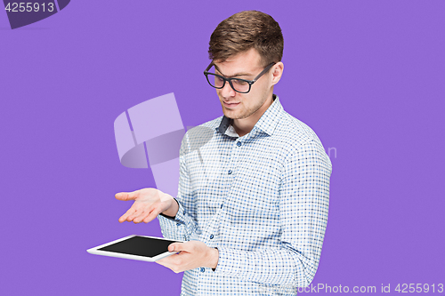 Image of The young man in a shirt working on laptop on lilac backgroundin