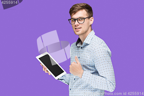 Image of The young man in a shirt working on laptop on lilac backgroundin